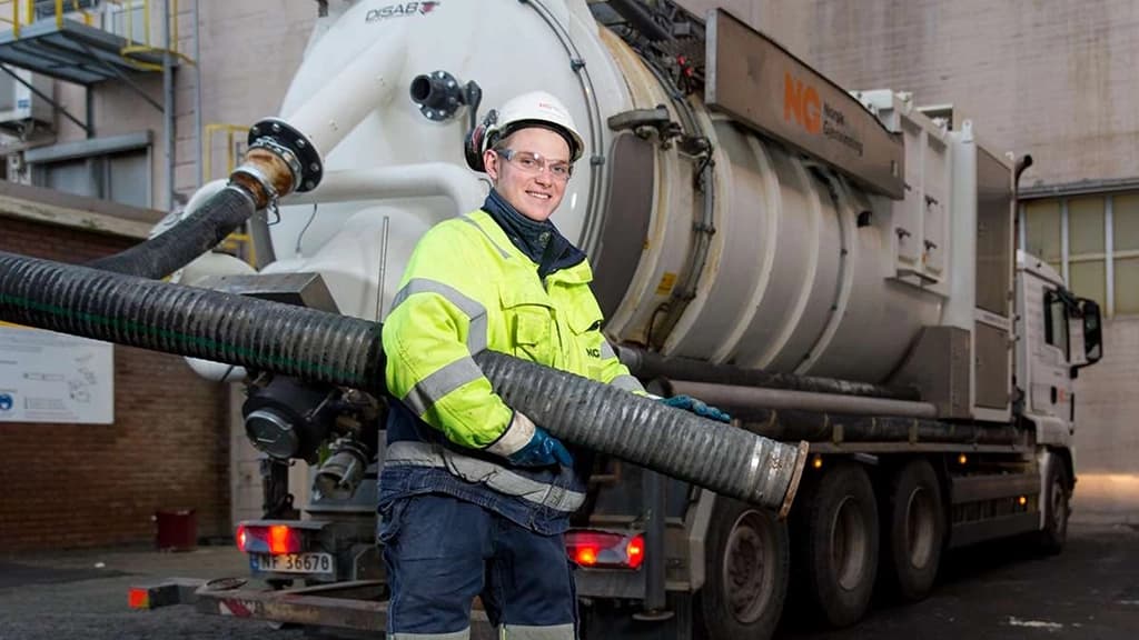 Arbeider med rør som suger slam. Foto.