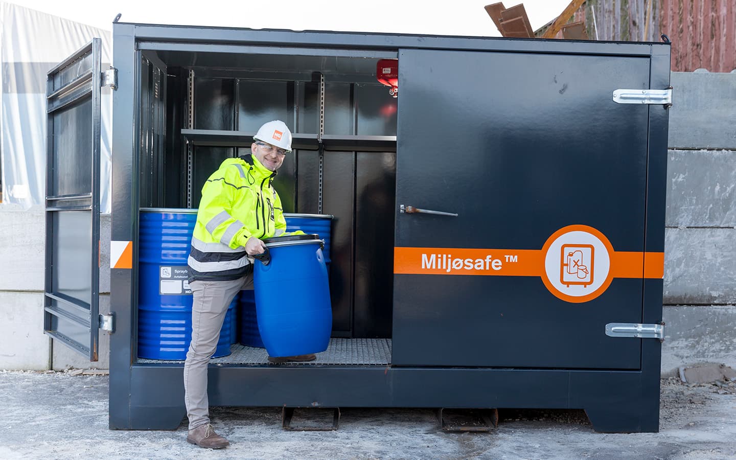 Mann står foran et miljøsafe-skap med farlig avfall. Foto.